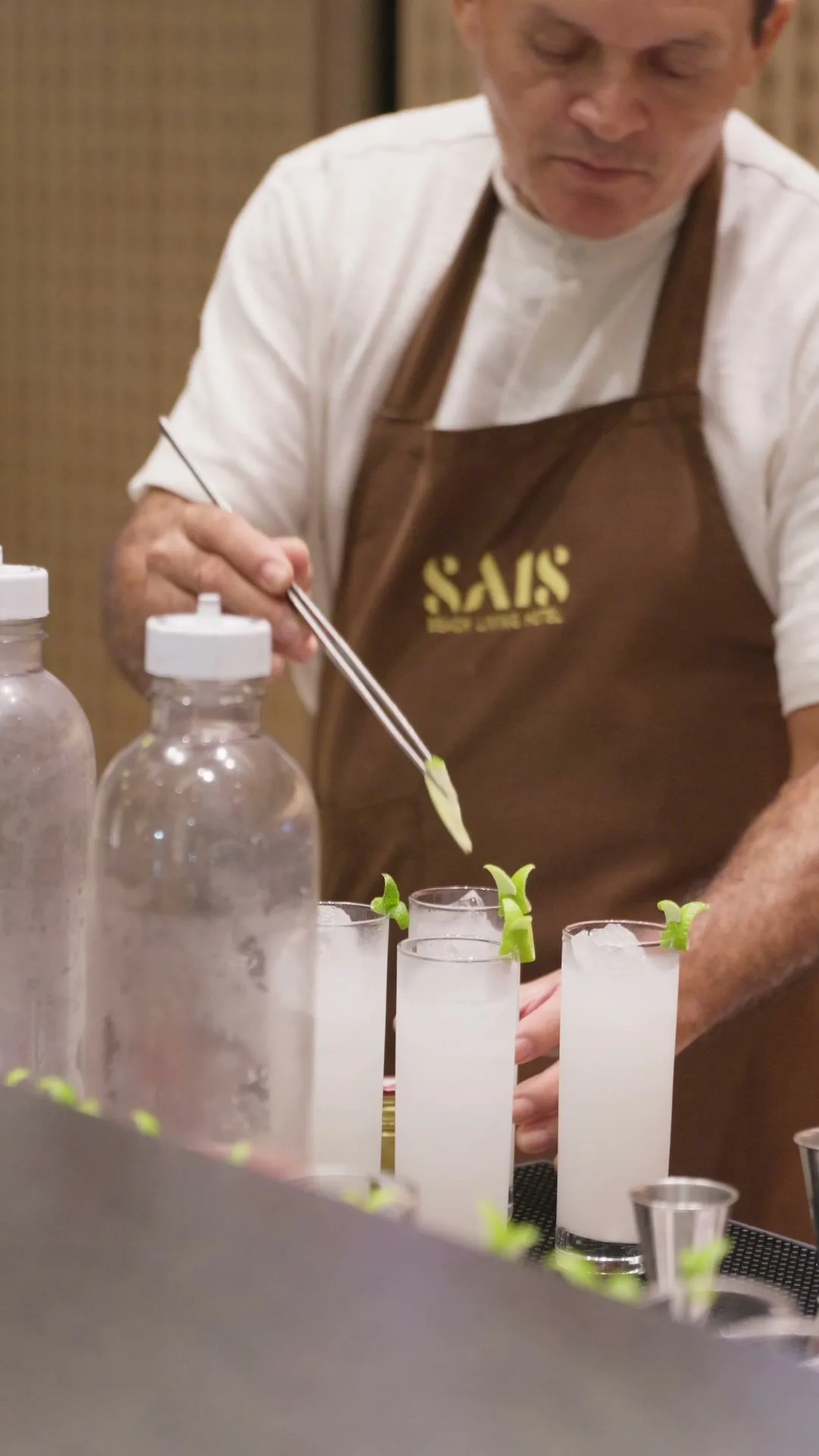 Bartender finalizando drinks com avental Sais